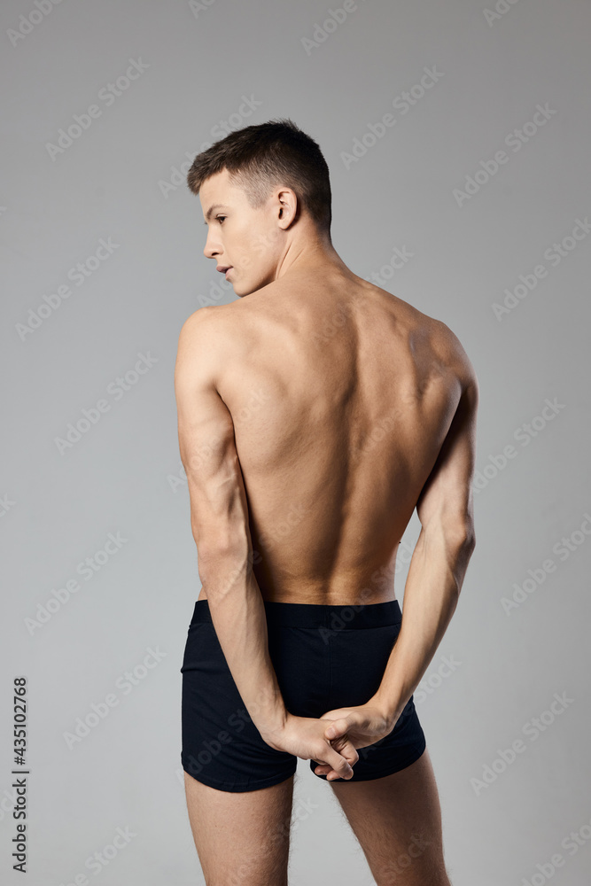handsome man with pumped up arm muscles naked back gray background model