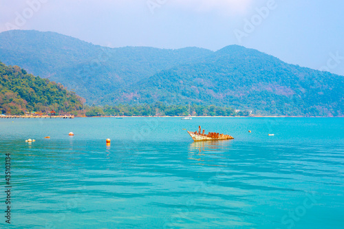 Marine tropical landscape. The remains of a broken ship against the backdrop of a sea pier and picturesque mountains