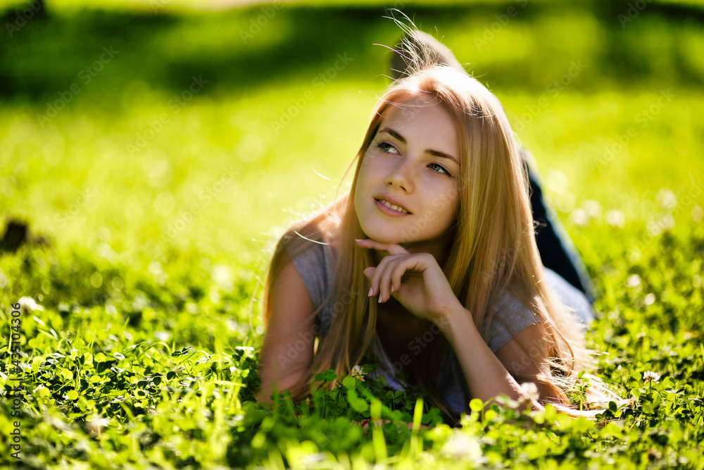 A beautiful girl lies in the park on the grass and dreamily looks around A beautiful girl lies in the park on the grass and dreamily looks around