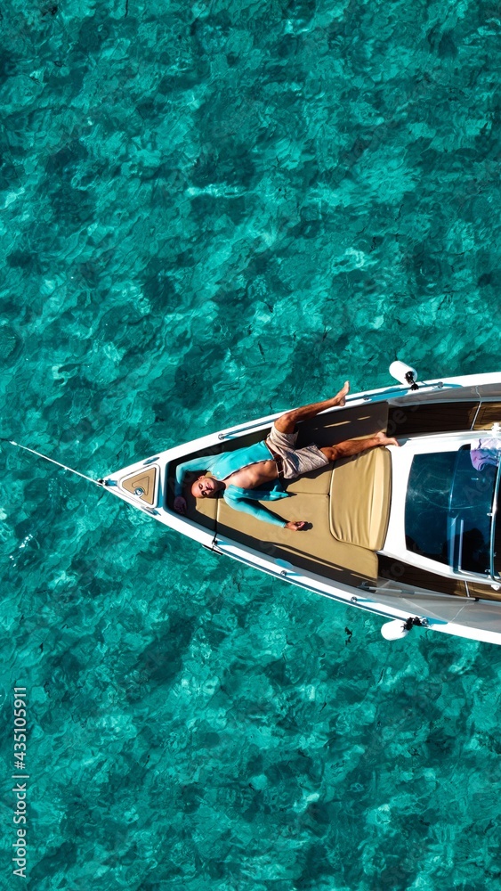 Obraz premium man resting on the deck of a boat in the sea of a beach of Majorca.Concept of holiday, leisure, travel, sun and beach