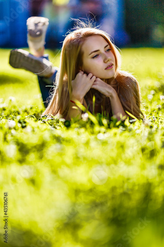 A beautiful girl lies in the park on the grass and dreamily looks around