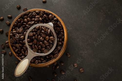 Coffee beans in wooden bowl on grunge background.