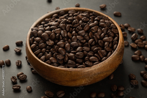 Coffee beans in wooden bowl on grunge background.