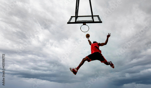 Foto Street basketball player making a powerful slam dunk on the court - Athletic mal