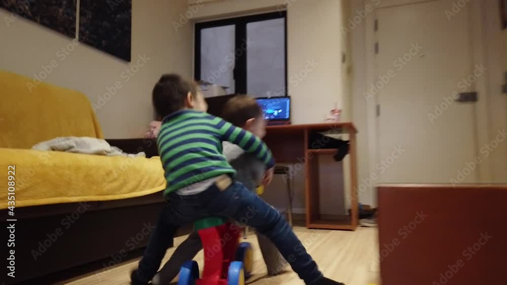 Cute toddlers siblings riding a plastic bike in the home during the lockdown. High quality 4k footage Cute toddlers siblings riding a plastic bike in the home during the lockdown. High quality 4k footage