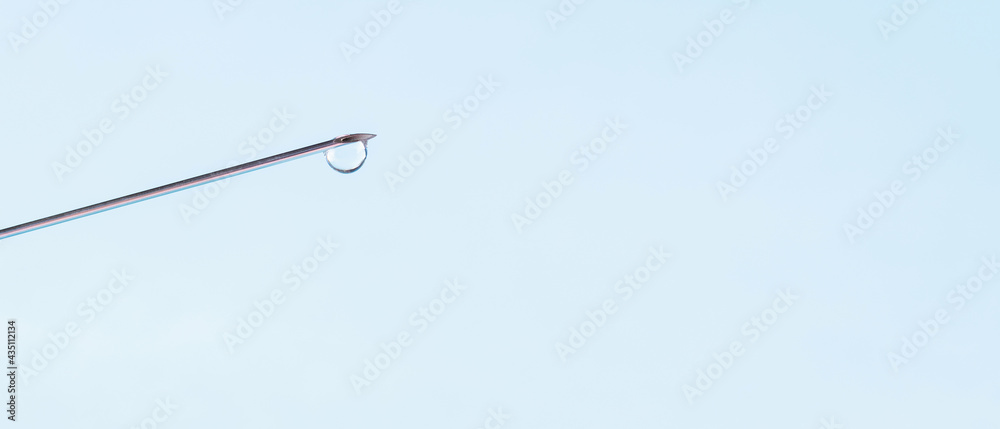 Vaccine syringe with drop on needle. Medical concept vaccination. Needle with a drop of vaccine on a blue background. Copy space Vaccine syringe with drop on needle. Medical concept vaccination. Needle with a drop of vaccine on a blue background. Copy space