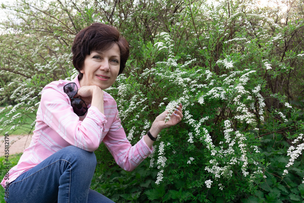 Portrait of a smiling Jewish woman next to a flowering spirea bush, natural background. Portrait of a smiling Jewish woman next to a flowering spirea bush, natural background.