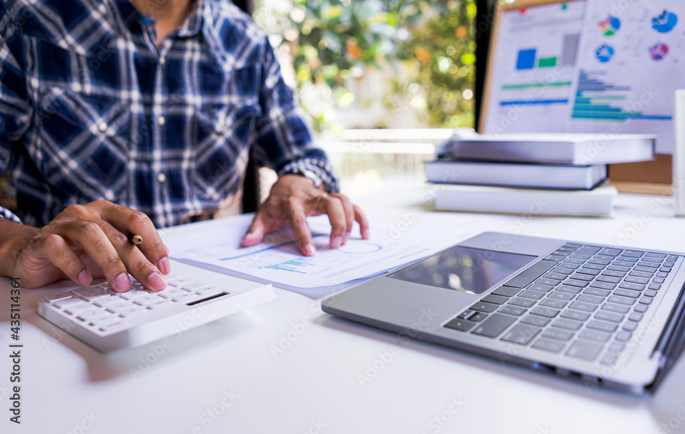 © Pravinrus - Business accounting concepts. Businessman or accountant using calculator to calculate business report, financial data report, accounting document, with laptop computer at home office. © Pravinrus - Business accounting concepts. Businessman or accountant using calculator to calculate business report, financial data report, accounting document, with laptop computer at home office.