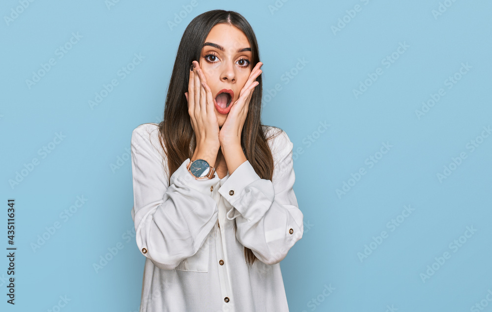 Young beautiful woman wearing casual white shirt afraid and shocked, surprise and amazed expression with hands on face Young beautiful woman wearing casual white shirt afraid and shocked, surprise and amazed expression with hands on face