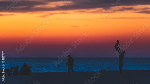 Father throwing child in air at beach, silhouette sunset © RandomHartz