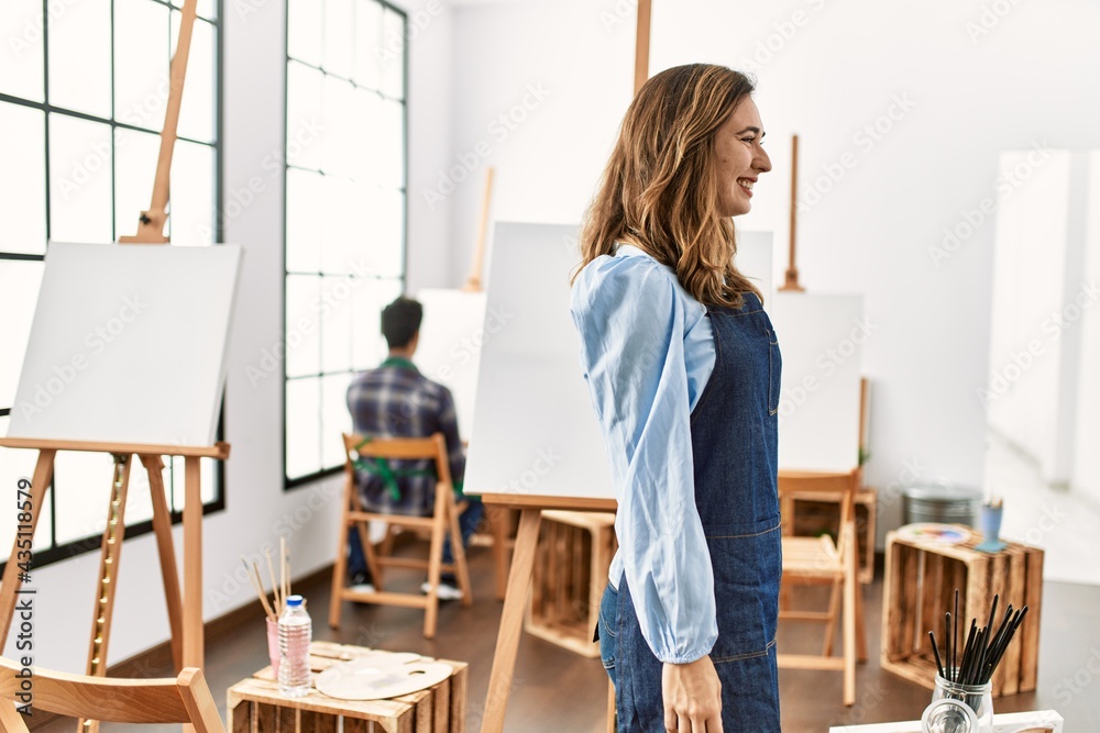 Young artist woman at art studio looking to side, relax profile pose with natural face with confident smile.