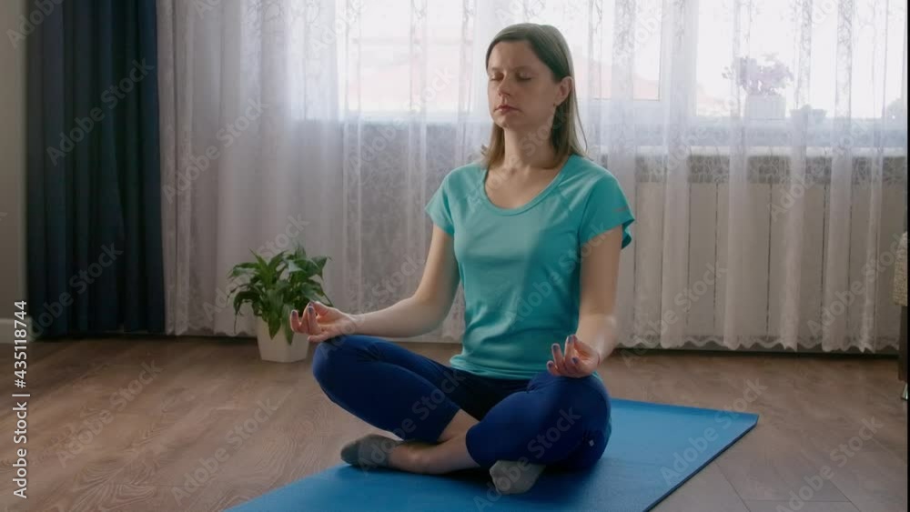 Woman meditating at home in the morning, quarantine leisure activity at home. Yoga practice by online courses.