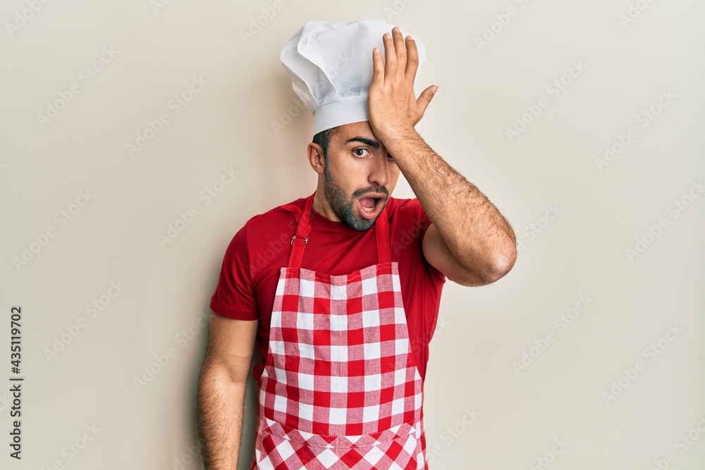 Young hispanic man wearing baker uniform surprised with hand on head for mistake, remember error. forgot, bad memory concept. Young hispanic man wearing baker uniform surprised with hand on head for mistake, remember error. forgot, bad memory concept.