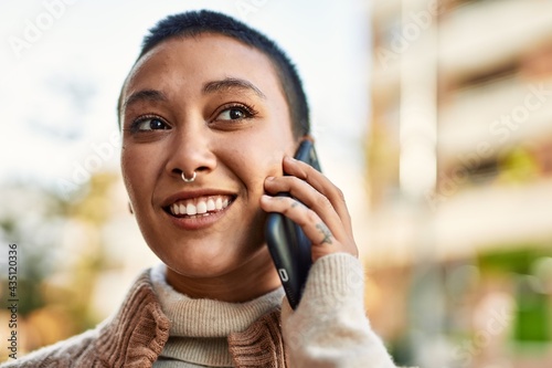 Young hispanic woman with short hair smiling happy speaking on the phone