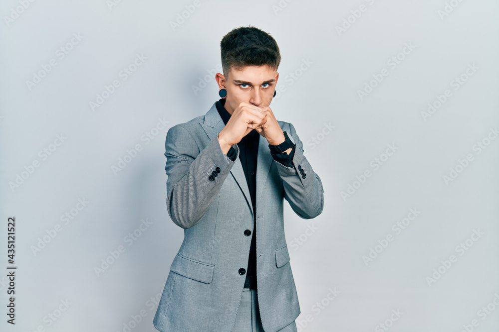Young caucasian boy with ears dilation wearing business jacket ready to fight with fist defense gesture, angry and upset face, afraid of problem Young caucasian boy with ears dilation wearing business jacket ready to fight with fist defense gesture, angry and upset face, afraid of problem