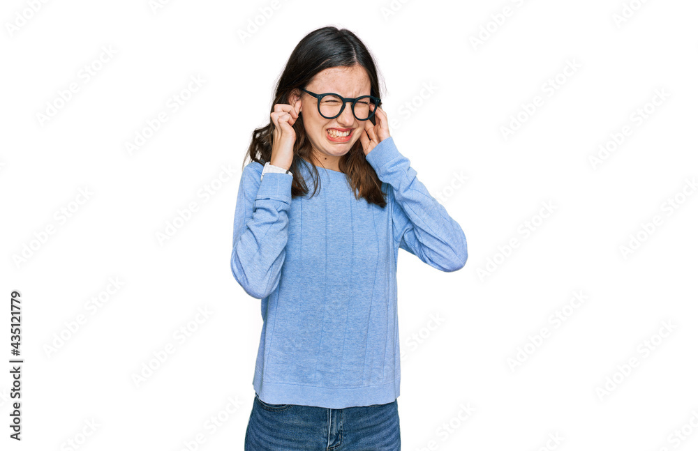 Young beautiful woman wearing casual clothes and glasses covering ears with fingers with annoyed expression for the noise of loud music. deaf concept. Young beautiful woman wearing casual clothes and glasses covering ears with fingers with annoyed expression for the noise of loud music. deaf concept.