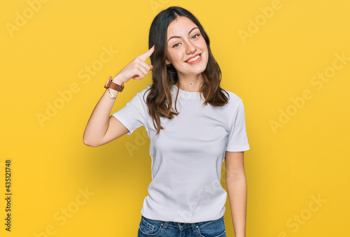 Young beautiful woman wearing casual white t shirt smiling pointing to head with one finger, great idea or thought, good memory