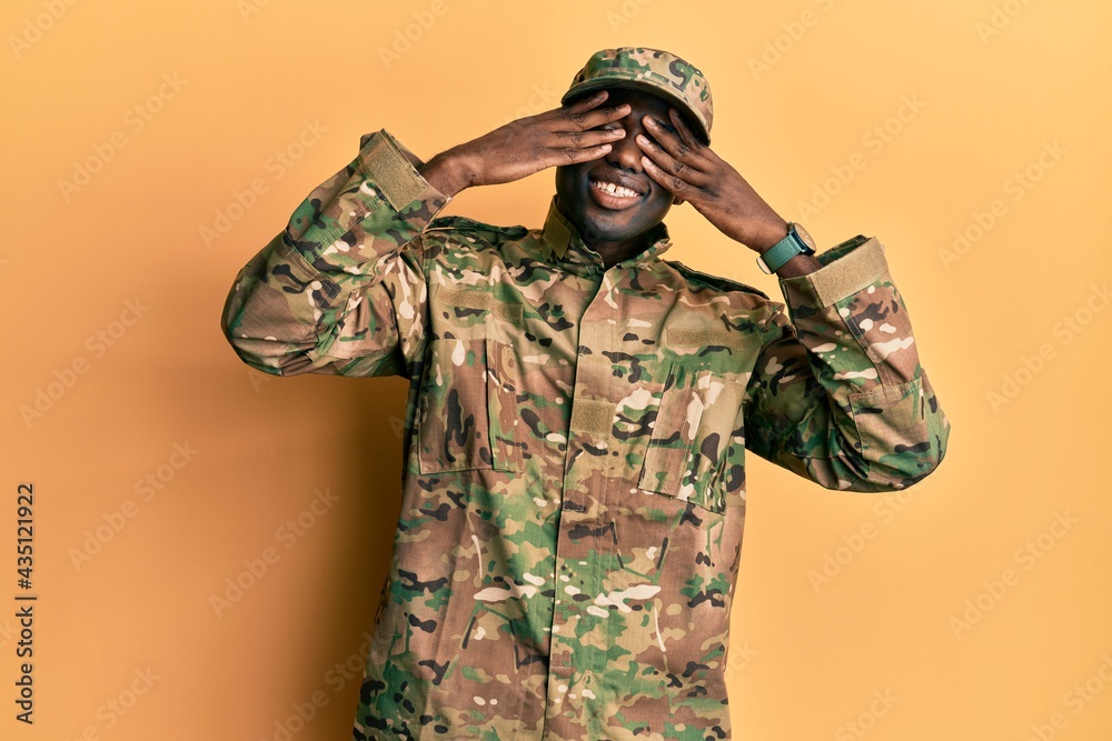 Young african american man wearing army uniform covering eyes with hands smiling cheerful and funny. blind concept. Young african american man wearing army uniform covering eyes with hands smiling cheerful and funny. blind concept.