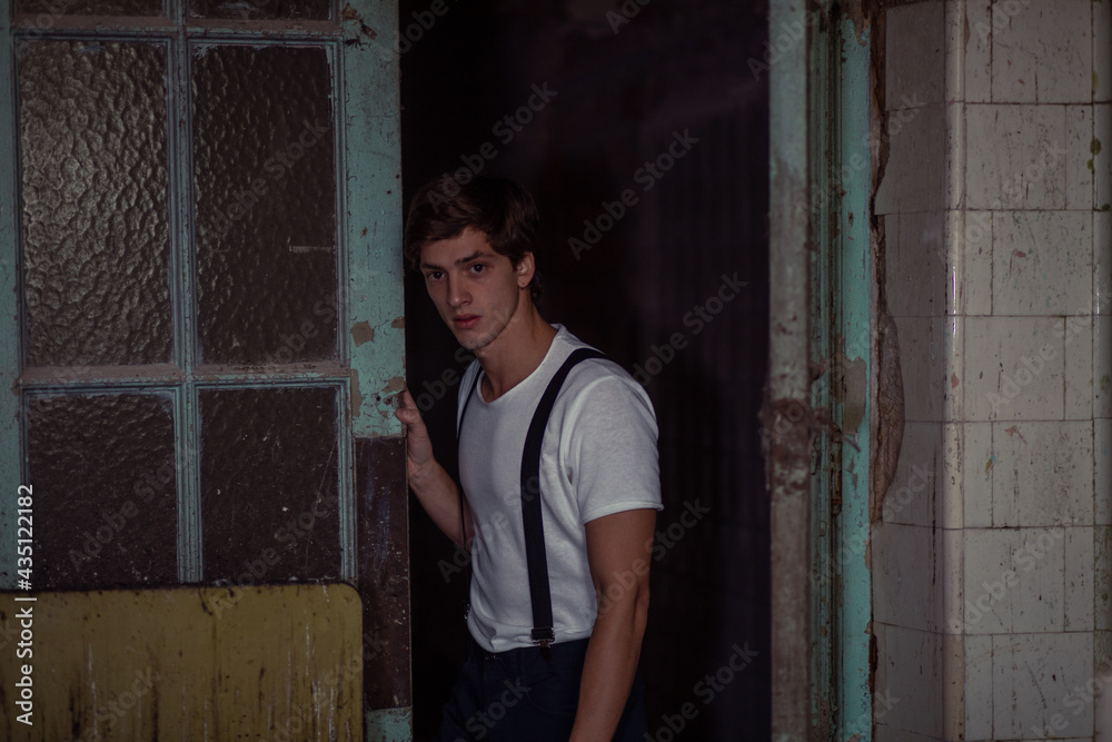 Joven en construcción abandonada vestido con gorro tiradores y camiseta Joven en construcción abandonada vestido con gorro tiradores y camiseta