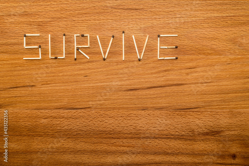 Matches on wooden table. Matches form the word "SURVIVE"