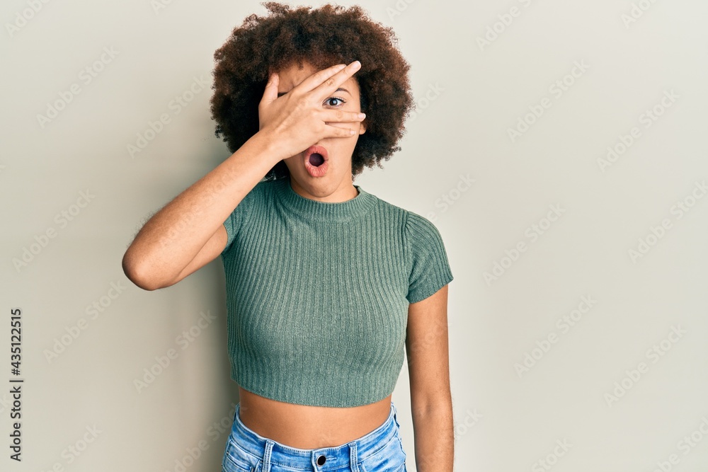 Young hispanic girl wearing casual clothes peeking in shock covering face and eyes with hand, looking through fingers afraid Young hispanic girl wearing casual clothes peeking in shock covering face and eyes with hand, looking through fingers afraid