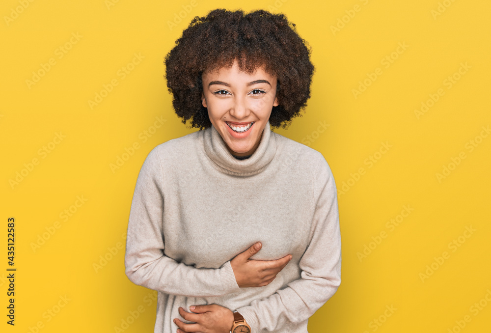 Young hispanic girl wearing wool winter sweater smiling and laughing hard out loud because funny crazy joke with hands on body.