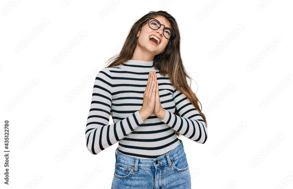 Young beautiful teen girl wearing casual clothes and glasses begging and praying with hands together with hope expression on face very emotional and worried. begging. Young beautiful teen girl wearing casual clothes and glasses begging and praying with hands together with hope expression on face very emotional and worried. begging.