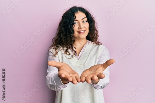 Quadro su tela Young brunette woman with curly hair wearing casual clothes smiling with hands palms together receiving or giving gesture