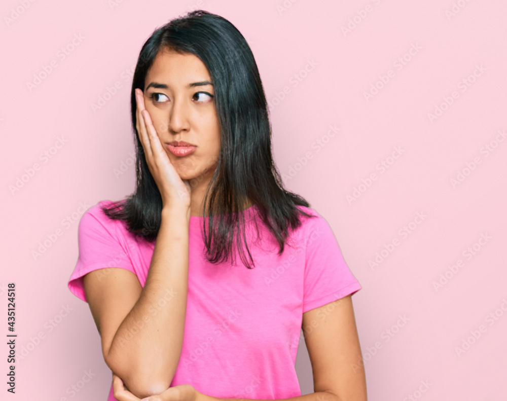 Beautiful asian young woman wearing casual pink t shirt thinking looking tired and bored with depression problems with crossed arms. Beautiful asian young woman wearing casual pink t shirt thinking looking tired and bored with depression problems with crossed arms.
