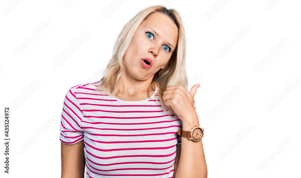 Young caucasian woman wearing casual clothes surprised pointing with hand finger to the side, open mouth amazed expression. Young caucasian woman wearing casual clothes surprised pointing with hand finger to the side, open mouth amazed expression.