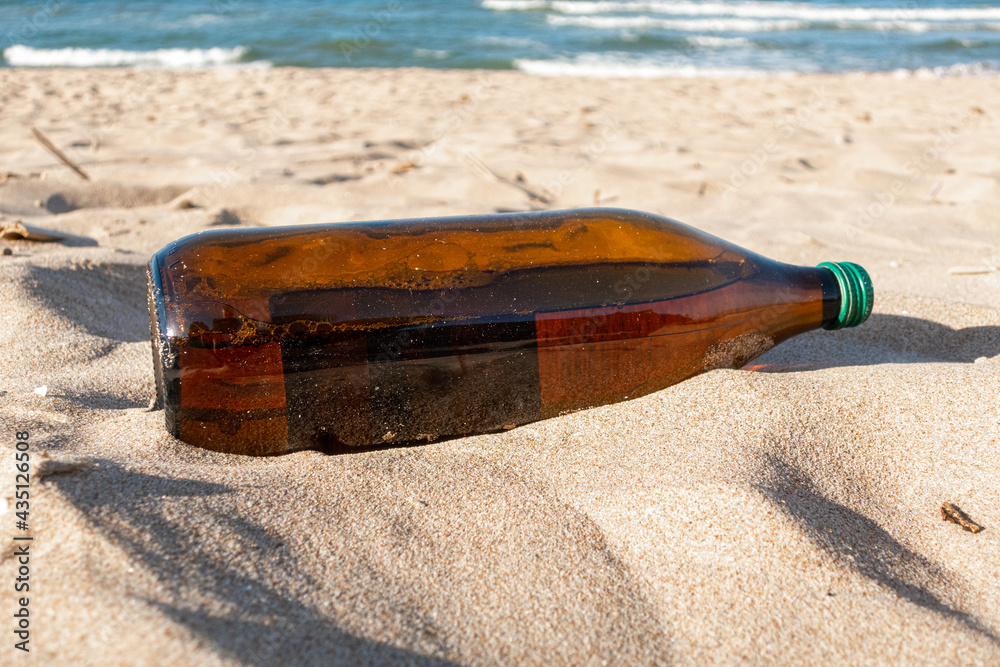 Beer bottle thrown in the sand on the beach.