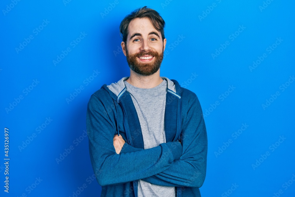 Caucasian man with beard wearing casual sweatshirt happy face smiling with crossed arms looking at the camera. positive person. Caucasian man with beard wearing casual sweatshirt happy face smiling with crossed arms looking at the camera. positive person.