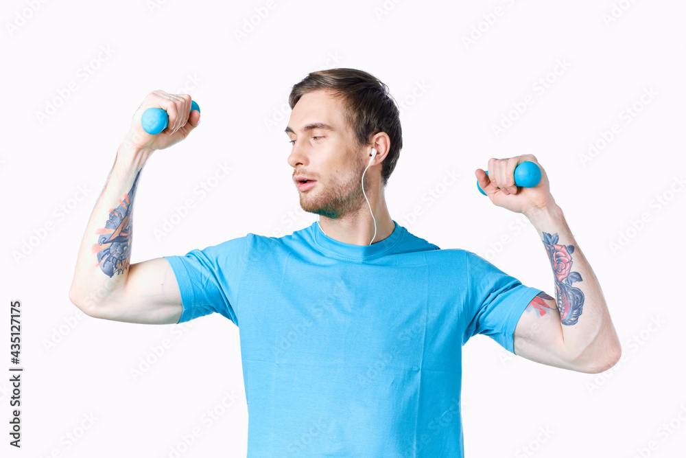 man doing exercises for the muscles of the arms with dumbbells on a light background man doing exercises for the muscles of the arms with dumbbells on a light background