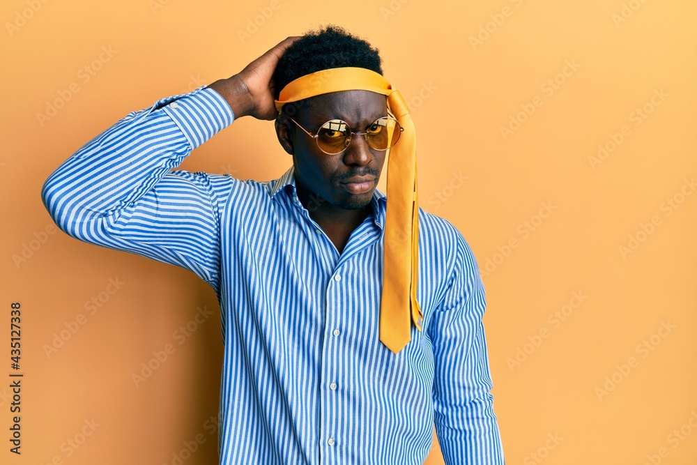 Handsome black man drunk wearing tie over head and sunglasses confuse and wonder about question. uncertain with doubt, thinking with hand on head. pensive concept. Handsome black man drunk wearing tie over head and sunglasses confuse and wonder about question. uncertain with doubt, thinking with hand on head. pensive concept.