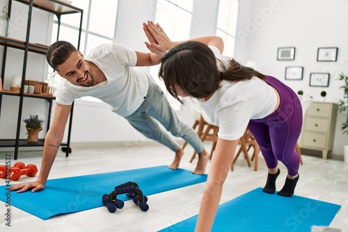 Young hispanic couple doing abs exercise at home