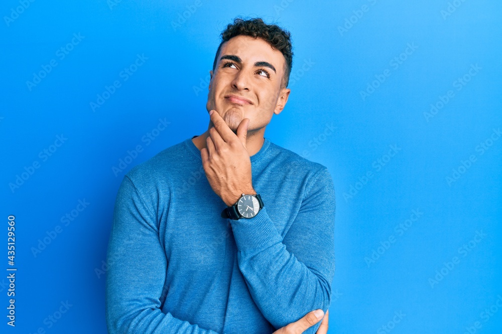 Hispanic young man wearing casual winter sweater thinking worried about a question, concerned and nervous with hand on chin