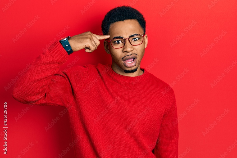 Young african american man pointing head with finger in shock face, looking skeptical and sarcastic, surprised with open mouth Young african american man pointing head with finger in shock face, looking skeptical and sarcastic, surprised with open mouth