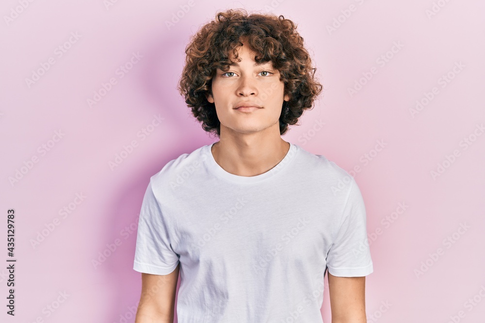 Obraz premium Handsome young man wearing casual white t shirt relaxed with serious expression on face. simple and natural looking at the camera.