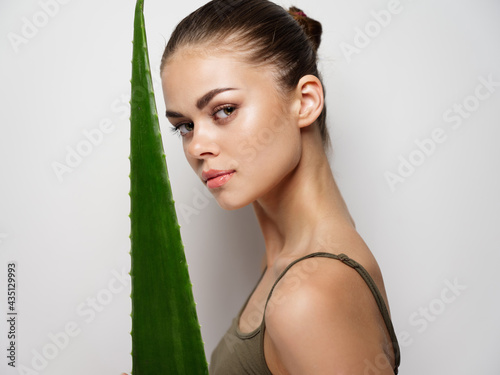 woman with green leaf on a light background and model clean skin 
