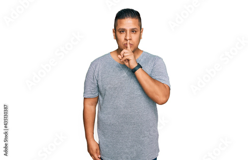 Young latin man wearing casual clothes asking to be quiet with finger on lips. silence and secret concept.