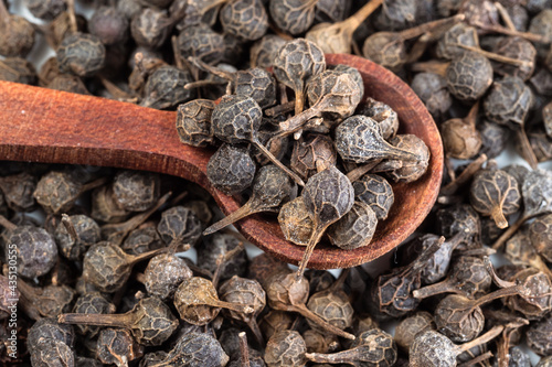 spoon on pile of dried cubeb pepper closeup photo