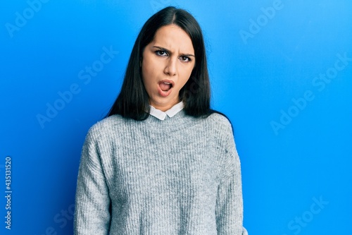 Young hispanic woman wearing casual clothes in shock face, looking skeptical and sarcastic, surprised with open mouth