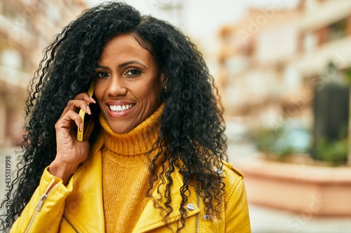 Middle age african american woman smiling happy talking on the smartphone at the city.