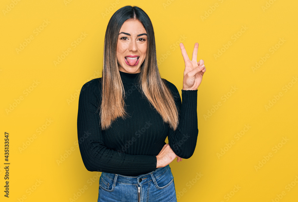 Young hispanic woman wearing casual clothes smiling with happy face winking at the camera doing victory sign. number two. Young hispanic woman wearing casual clothes smiling with happy face winking at the camera doing victory sign. number two.