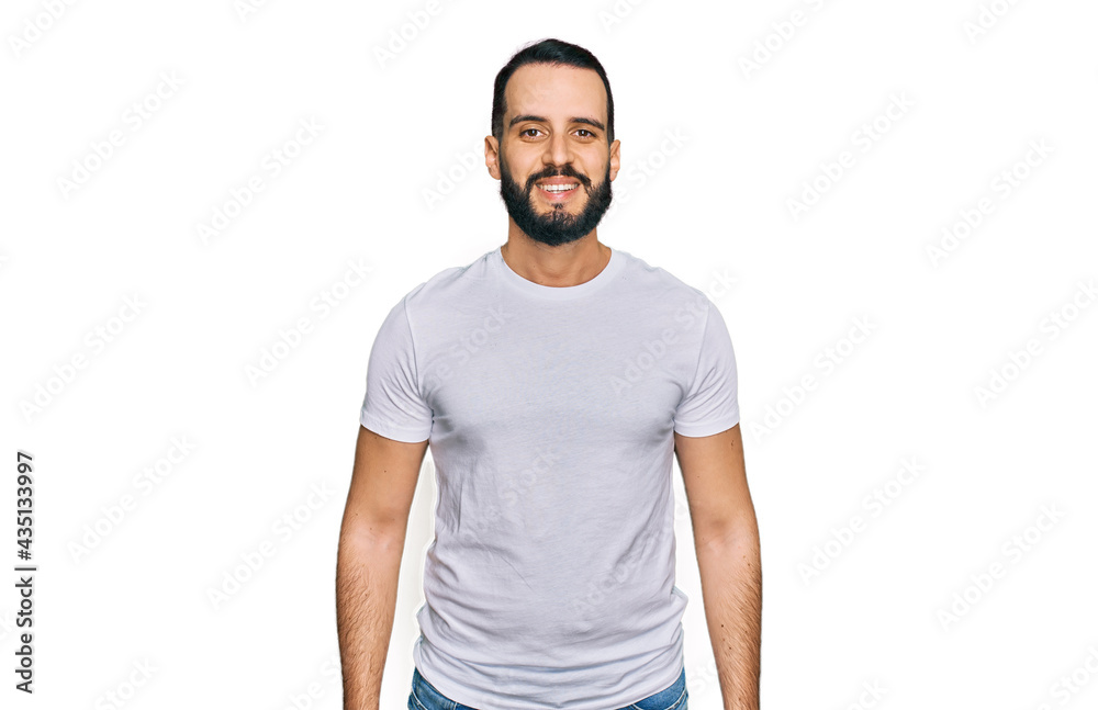 Fototapeta premium Young man with beard wearing casual white t shirt with a happy and cool smile on face. lucky person.