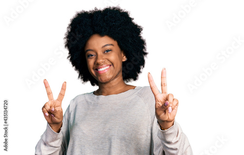 Young african american woman wearing casual clothes smiling looking to the camera showing fingers doing victory sign. number two. © Krakenimages.com