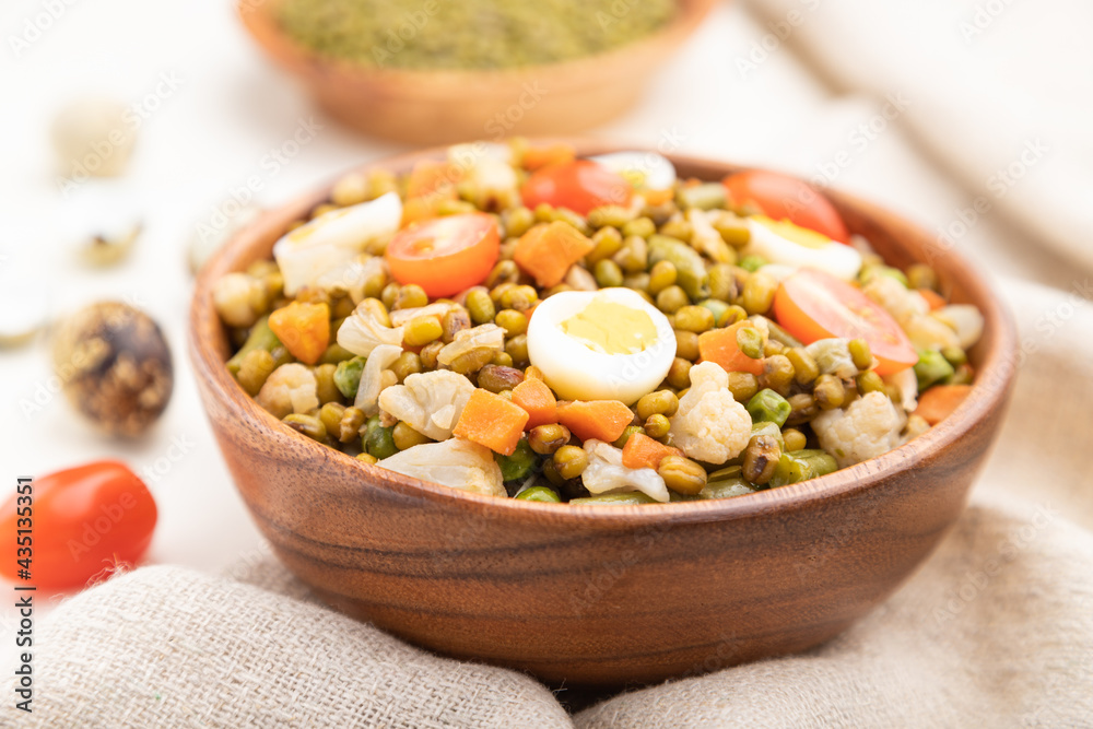 Mung bean porridge with quail eggs, tomatoes and microgreen sprouts on a white wooden background. Side view, selective focus. Mung bean porridge with quail eggs, tomatoes and microgreen sprouts on a white wooden background. Side view, selective focus.