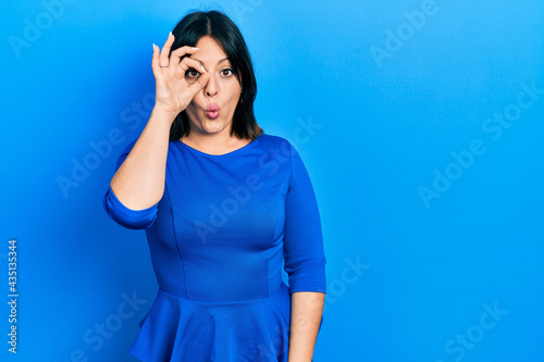 Young hispanic woman wearing casual clothes doing ok gesture shocked with surprised face, eye looking through fingers. unbelieving expression.