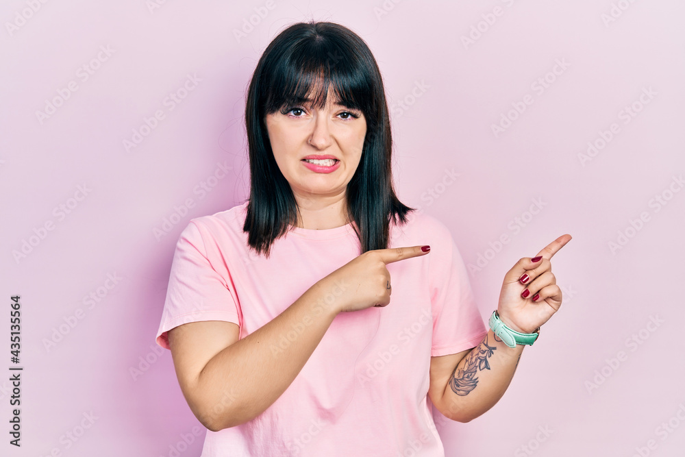 Young hispanic woman wearing casual clothes pointing aside worried and nervous with both hands, concerned and surprised expression Young hispanic woman wearing casual clothes pointing aside worried and nervous with both hands, concerned and surprised expression
