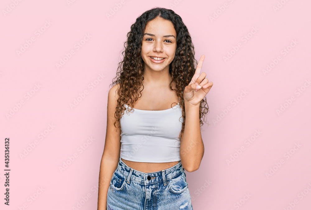 Teenager hispanic girl wearing casual clothes showing and pointing up with finger number one while smiling confident and happy. Teenager hispanic girl wearing casual clothes showing and pointing up with finger number one while smiling confident and happy.